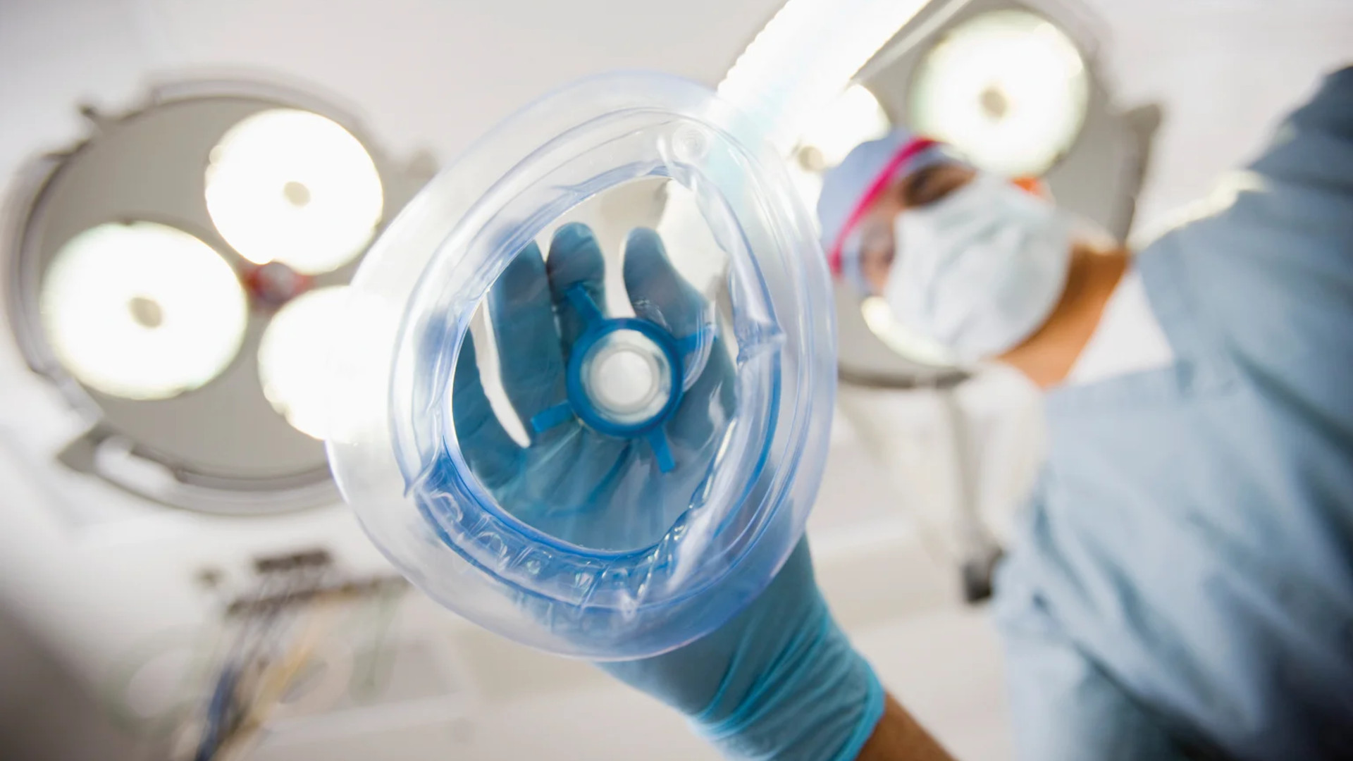 Anesthesiologist holding an anesthesia mask under operating room lights before a case
